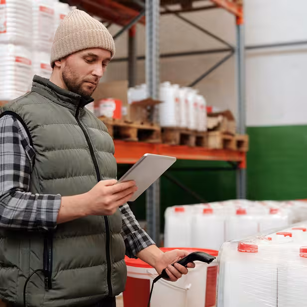 A small business manufacturer uses a scanner and tablet to check inventory at his shop.