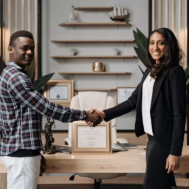 The owner of a small law firm shakes hands with a new partner.