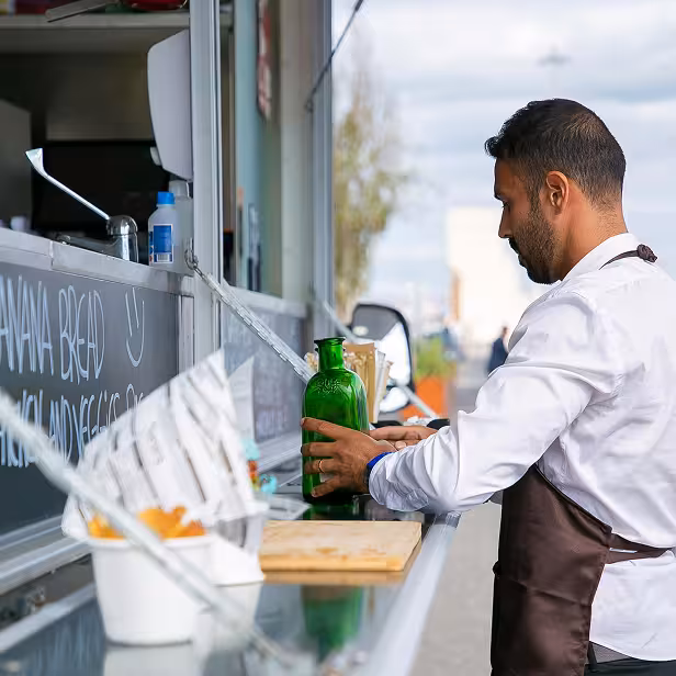 Small business caterer adjusts a jar on an outdoor food buffet.