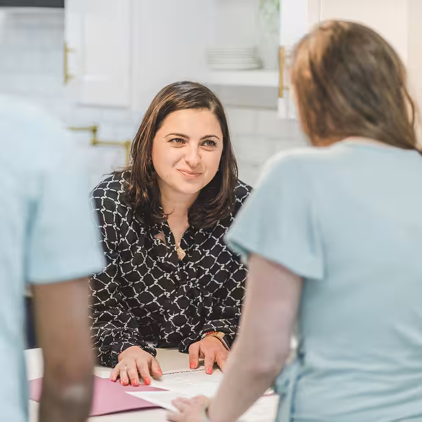 A small business insurance agency owner reviews policies with two clients.