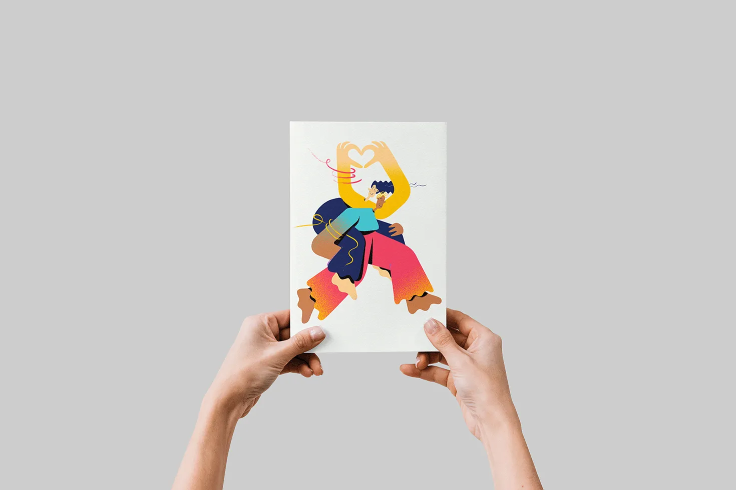 Two hands hold up a sheet of paper with an illustration showing two abstractly colorful illustrated people. One person is carrying the other piggyback and the second person is forming a heart with their hands.
