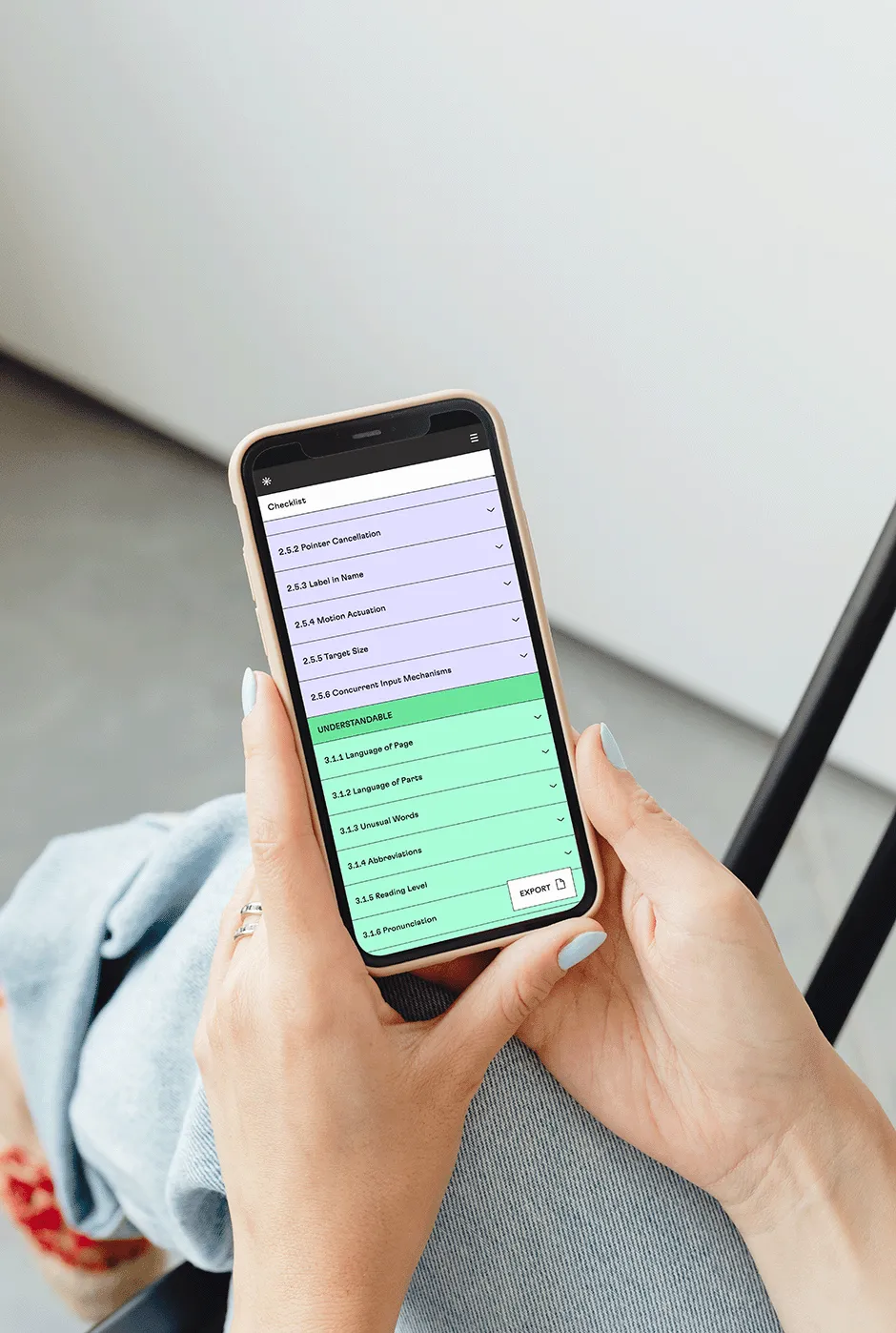 Hands holding an iPhone on which the colorful Perspectives website can be seen. The current view shows the custom checklist, which lists the various guidelines of the Web Content Accessibility Guidelines. A floating action button with the label "Export" can be seen at the bottom right of the screen.