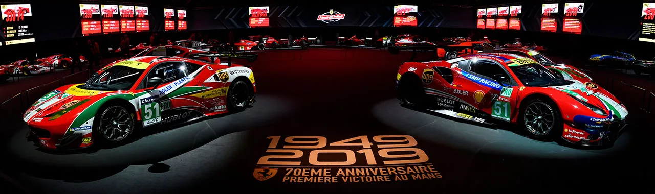 Image de deux voitures sportives exposées dans un salon automobile, mises en valeur par un éclairage sophistiqué et un décor moderne, attirant l’attention des visiteurs.