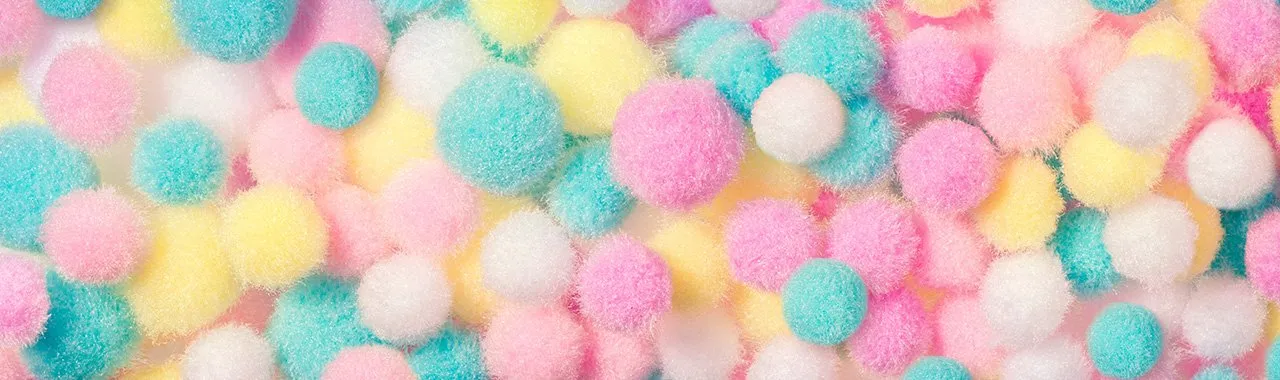 Image de pompons colorés, soigneusement triés par dégradés de couleurs, allant des teintes les plus claires aux plus foncées.
