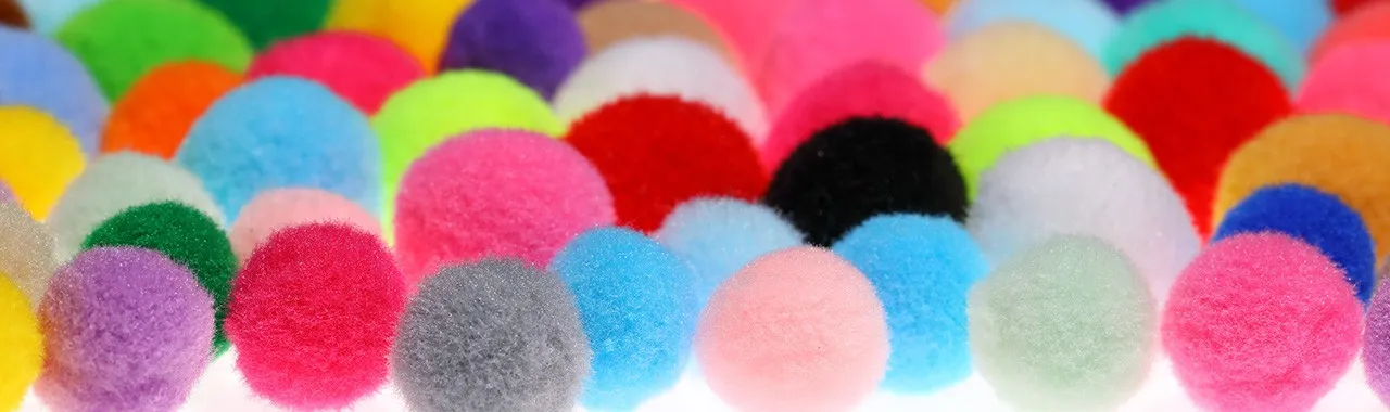 Image de pompons colorés, soigneusement triés par dégradés de couleurs, allant des teintes les plus claires aux plus foncées.