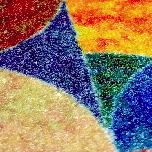 Gros plan sur une moquette colorée avec des formes géométriques en bleu, jaune, vert, orange et beige.