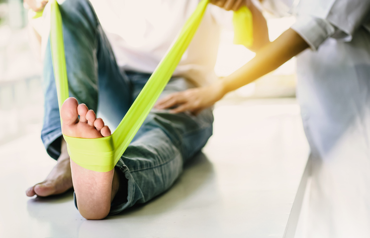 Physiotherapist guiding a resistance band exercise for ankle rehabilitation