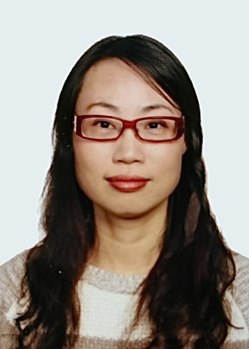 Portrait of a woman with long dark hair wearing red glasses and a beige and white sweater against a light background. Acupuncturist in richmond