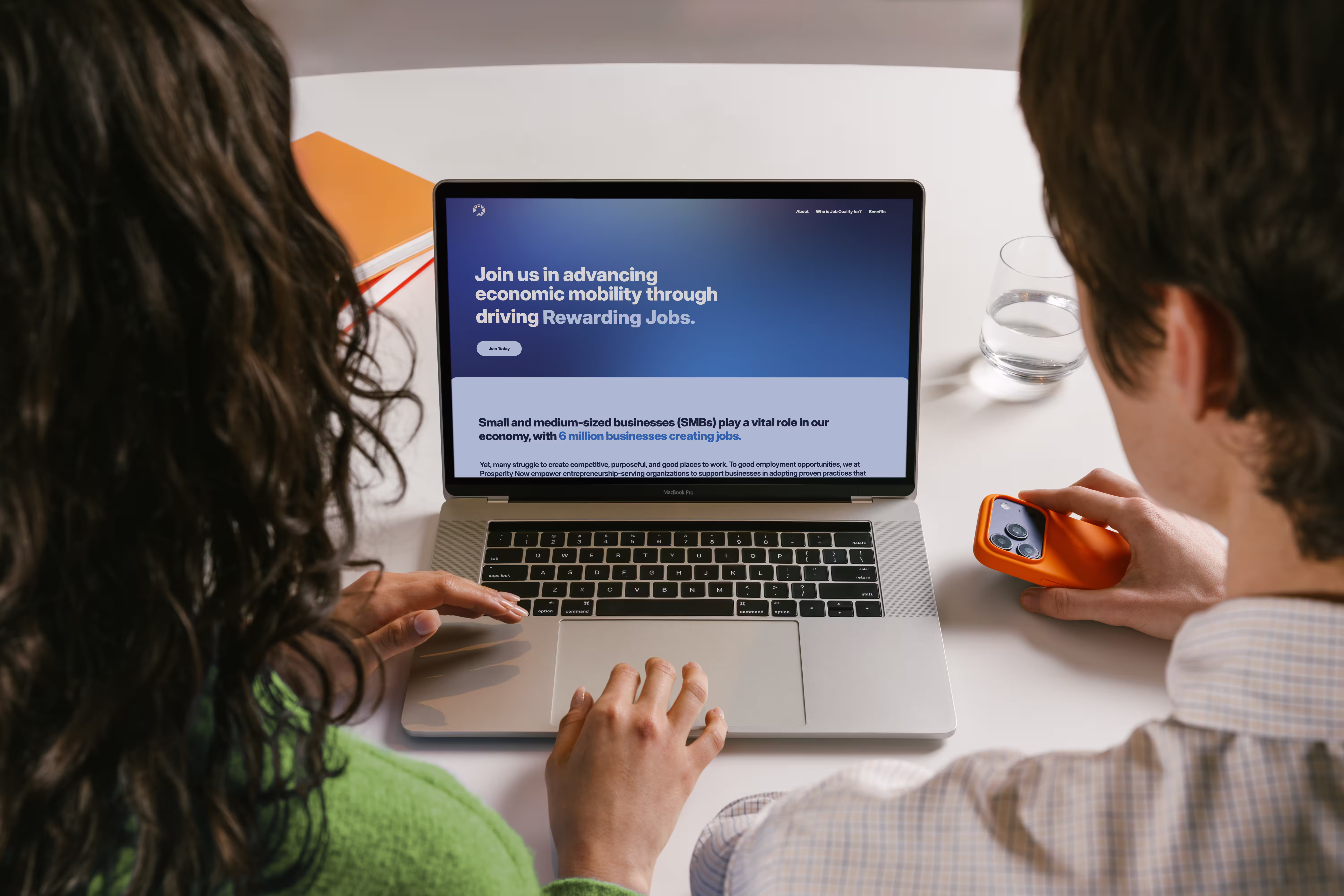 Two people viewing a laptop screen displaying a website about advancing economic mobility via rewarding jobs.