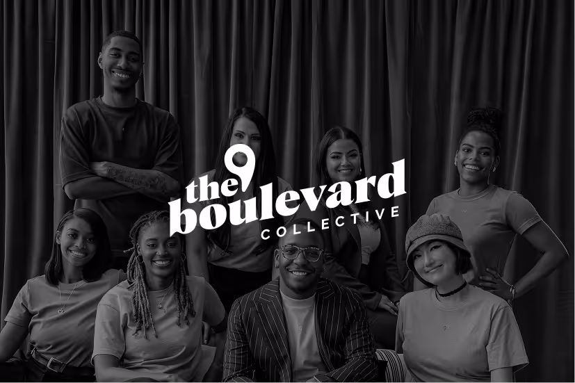 Smiling diverse group of seven young adults posing in front of dark curtains with The Boulevard Collective logo.