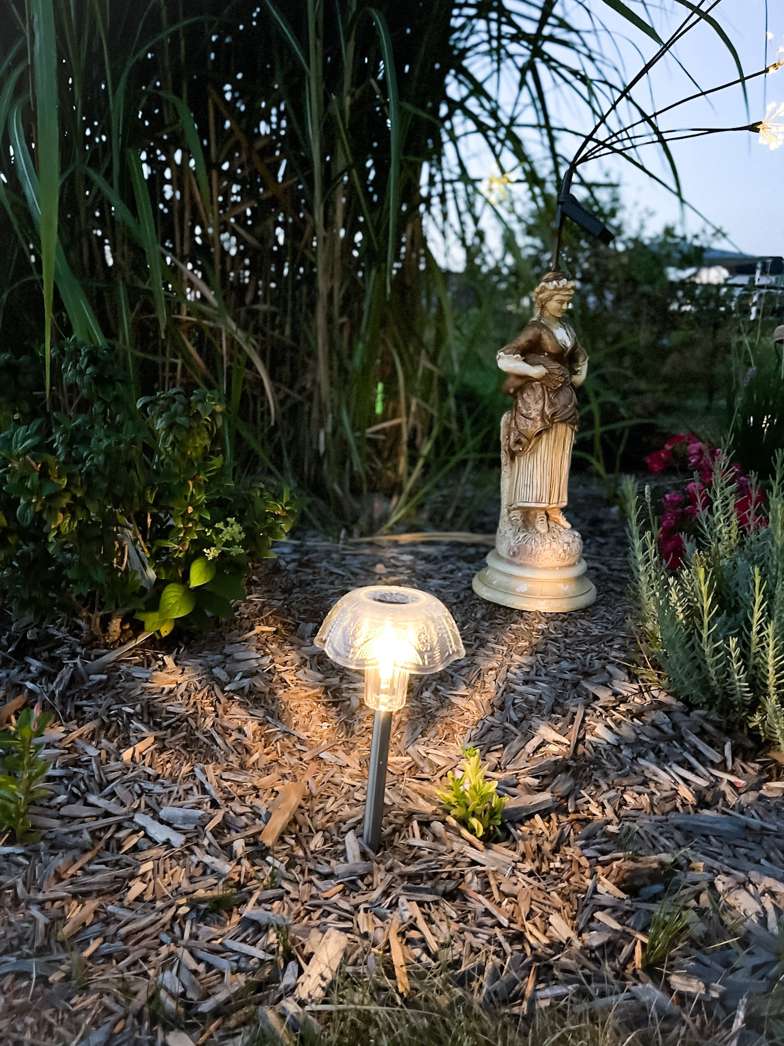 Customized solar light in a flower bed with tall grass, hydrangeas, and lavender.