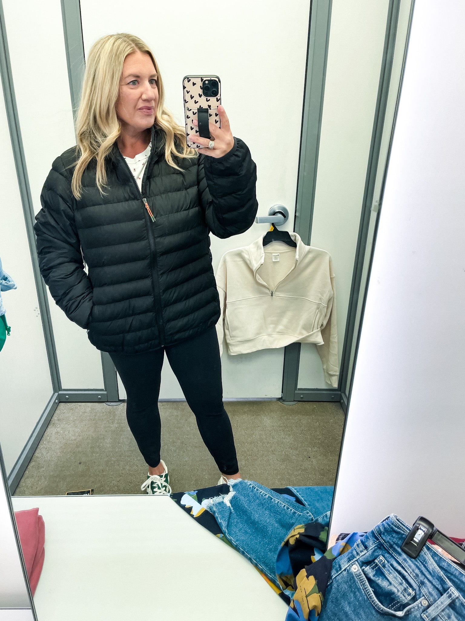 midsize woman trying on clothes at walmart - black puffer coat and black leggings