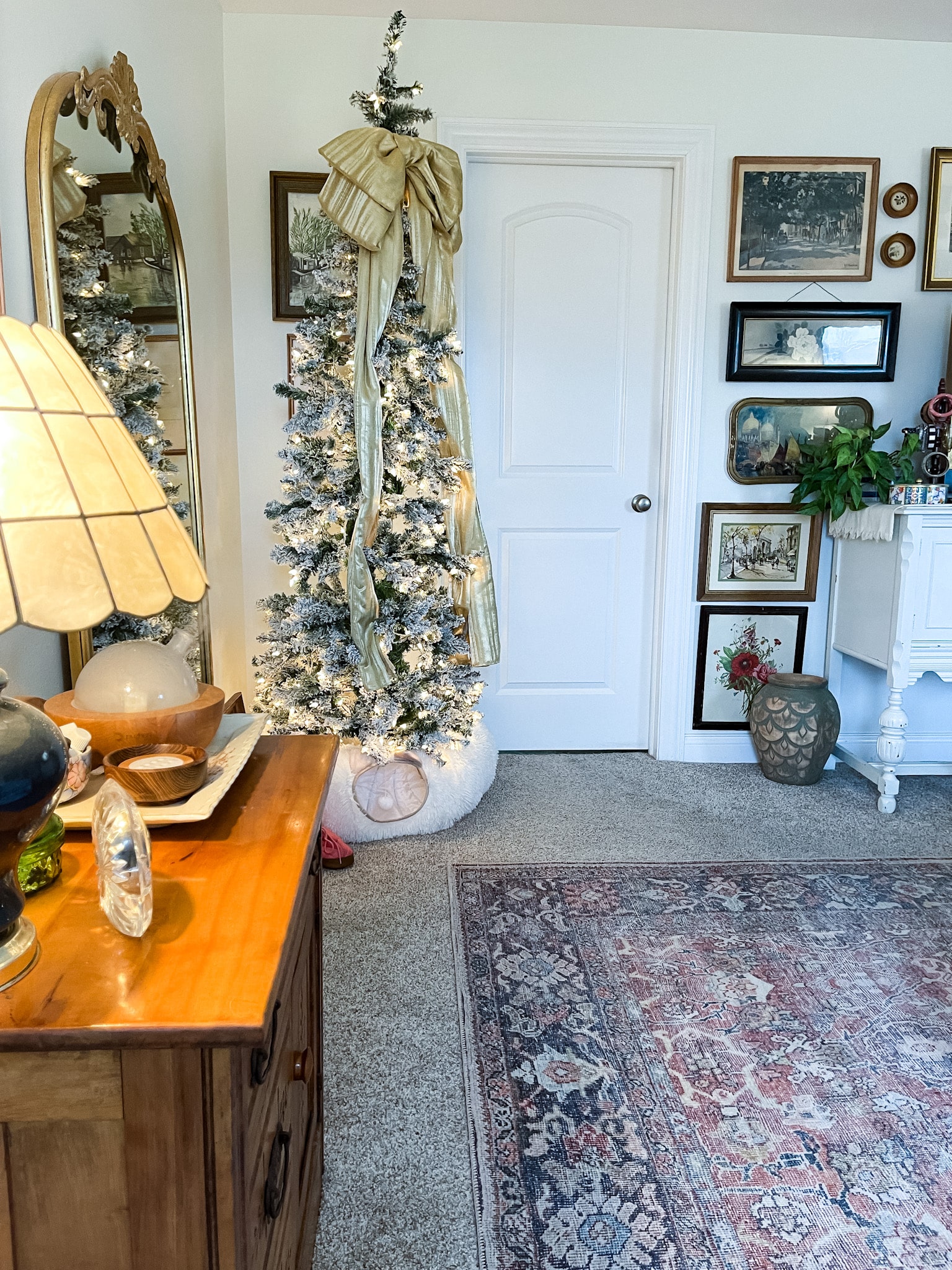 Bedroom with a flocked pencil tree in the corner and a buffet with a tv on it surrounded by a gallery wall