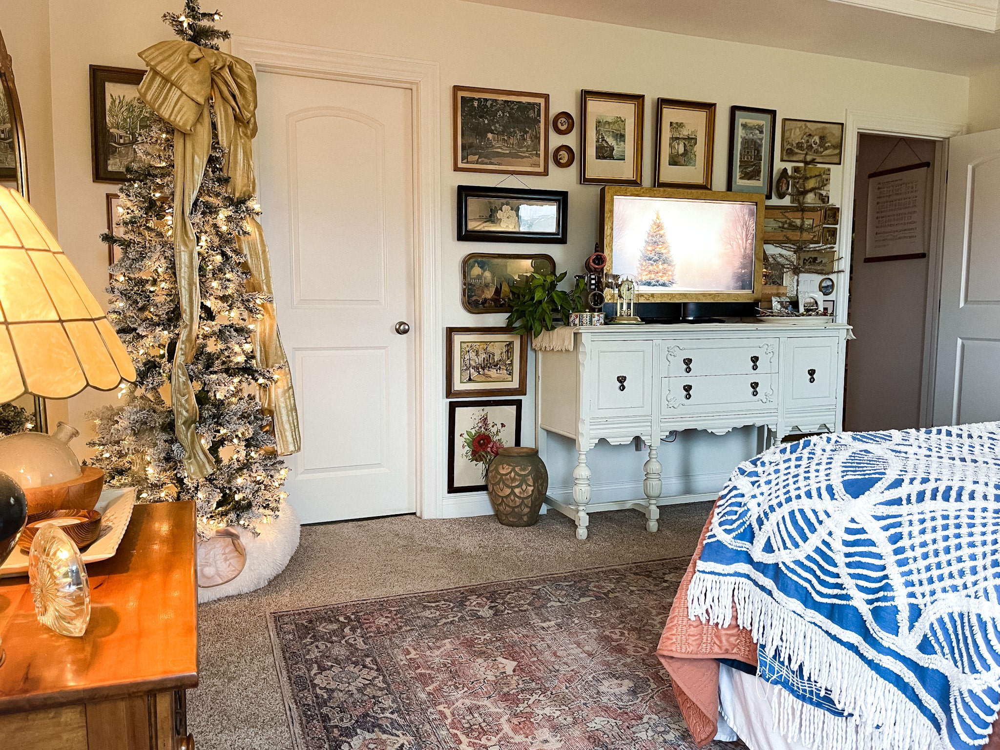 Bedroom with a flocked pencil tree in the corner and a buffet with a tv on it surrounded by a gallery wall