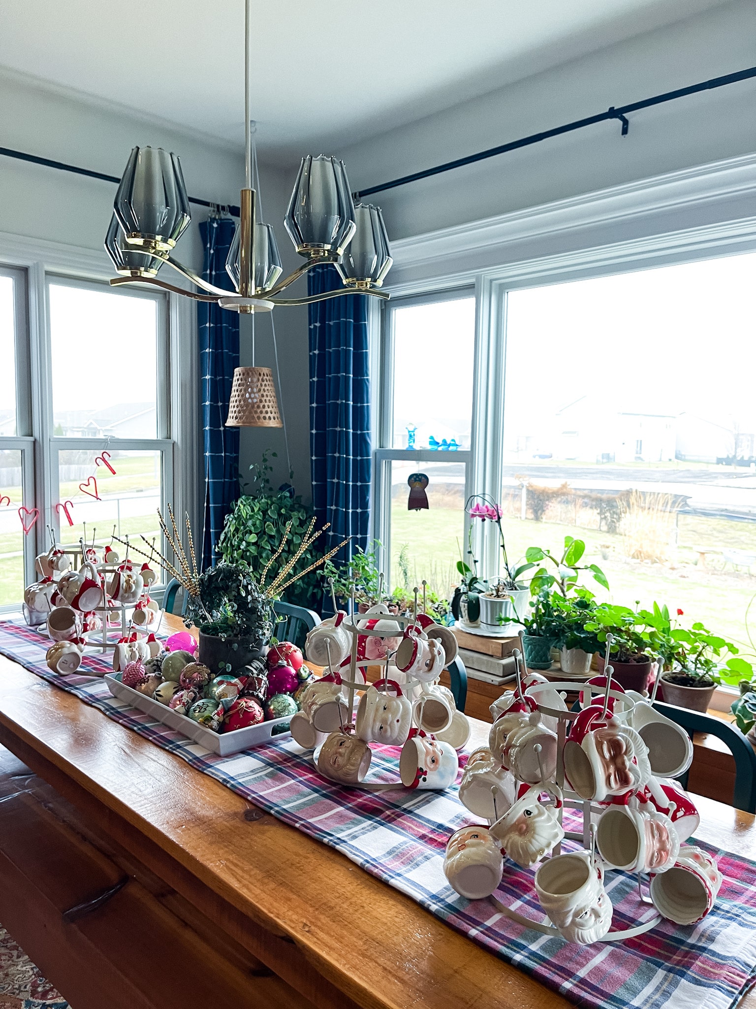 farmhouse table filled with vintage christmas decorations, including santa mugs