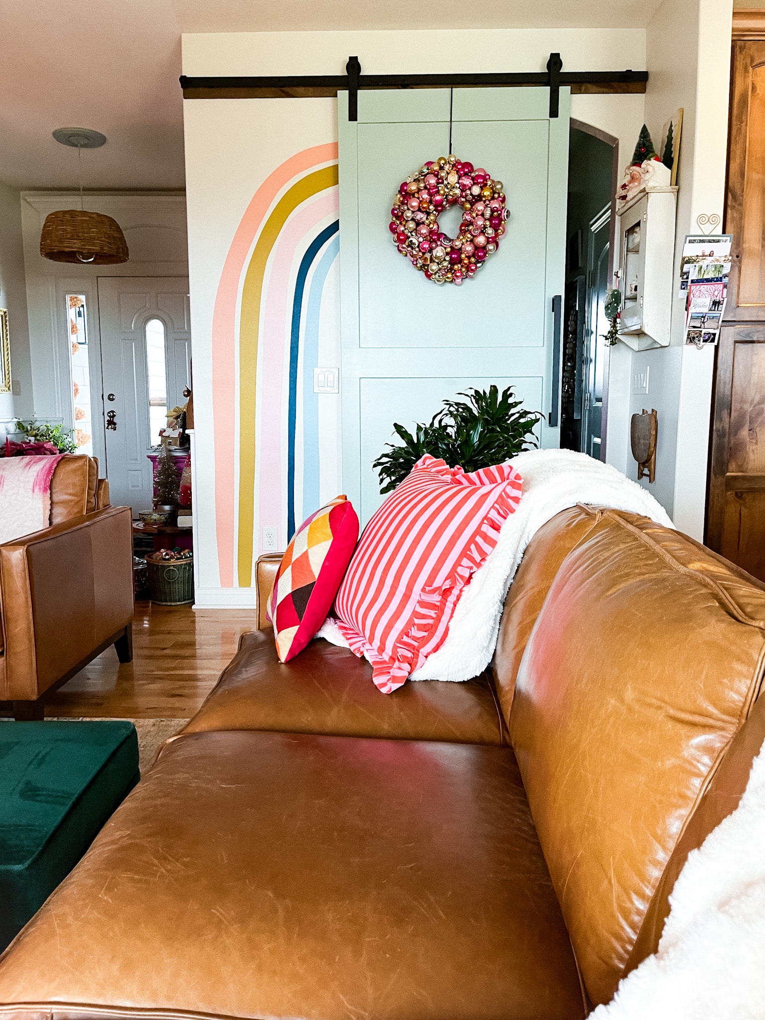 view of a living room with two leather couches, facing toward a blue barn door with an ornament wreath on it