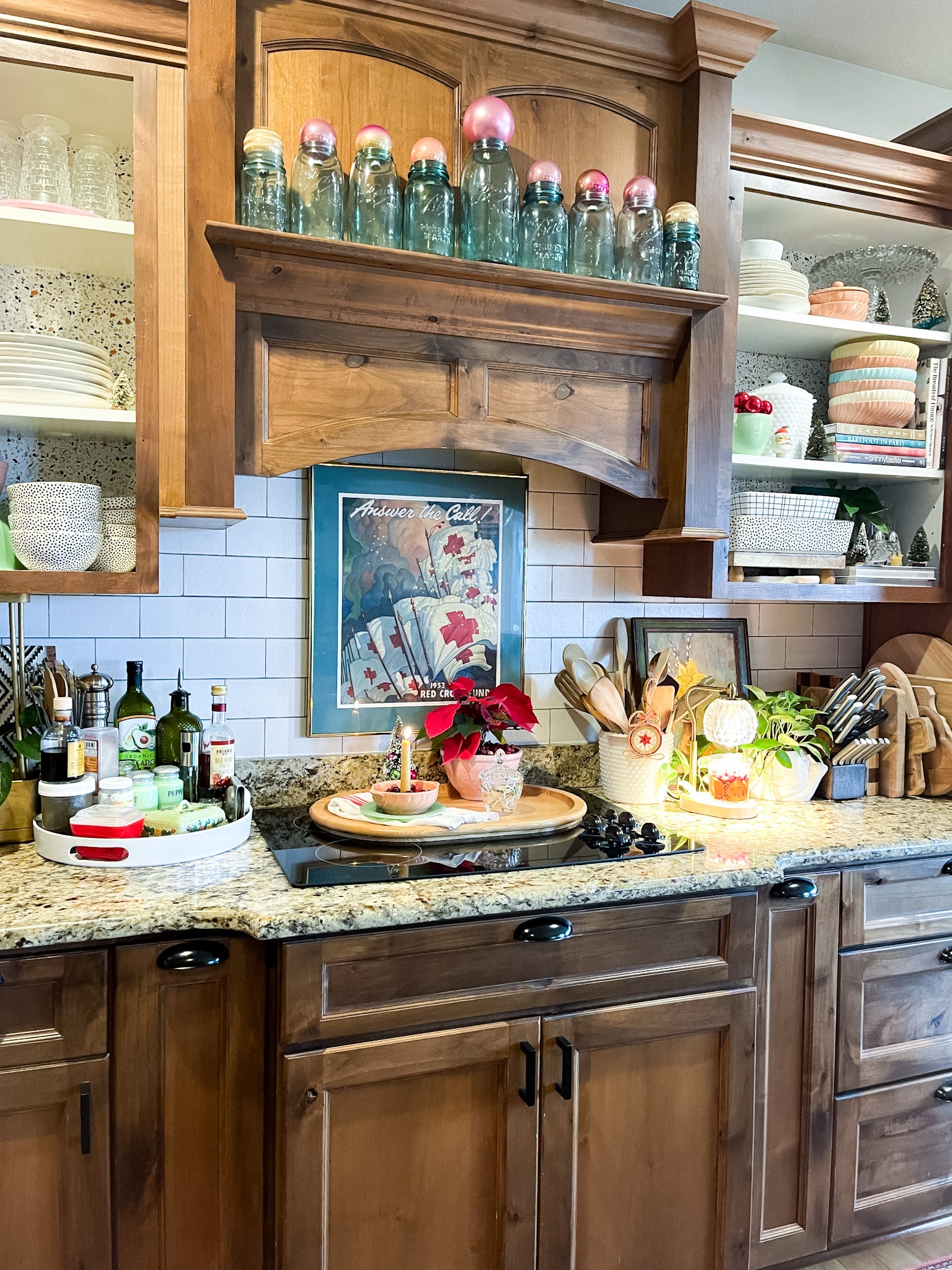 kitchen with medium wood cabinets, a blue painted island, open shelving, and three globe pendant lights. Bits of vintage Christmas scattered throughout.