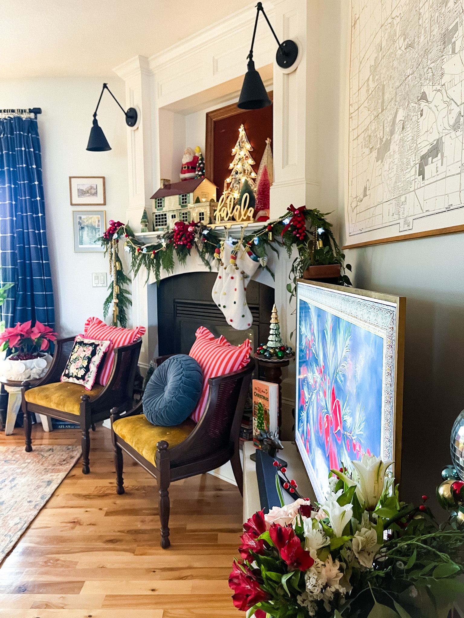 fireplace and mantel decorated for christmas, two accent chairs in front with pillos, and an art tv