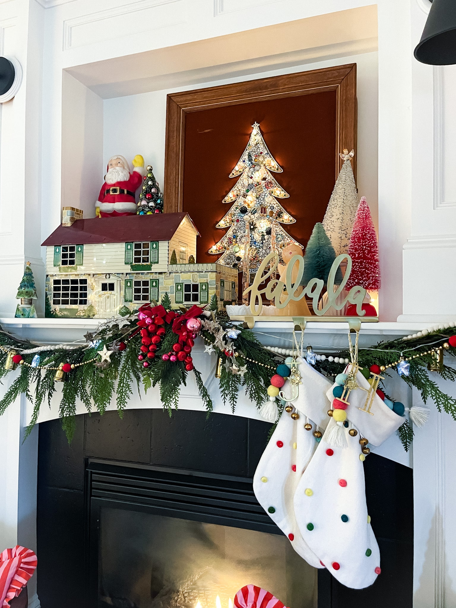 fireplace and mantel decorated for christmas, two accent chairs in front with pillos, and an art tv