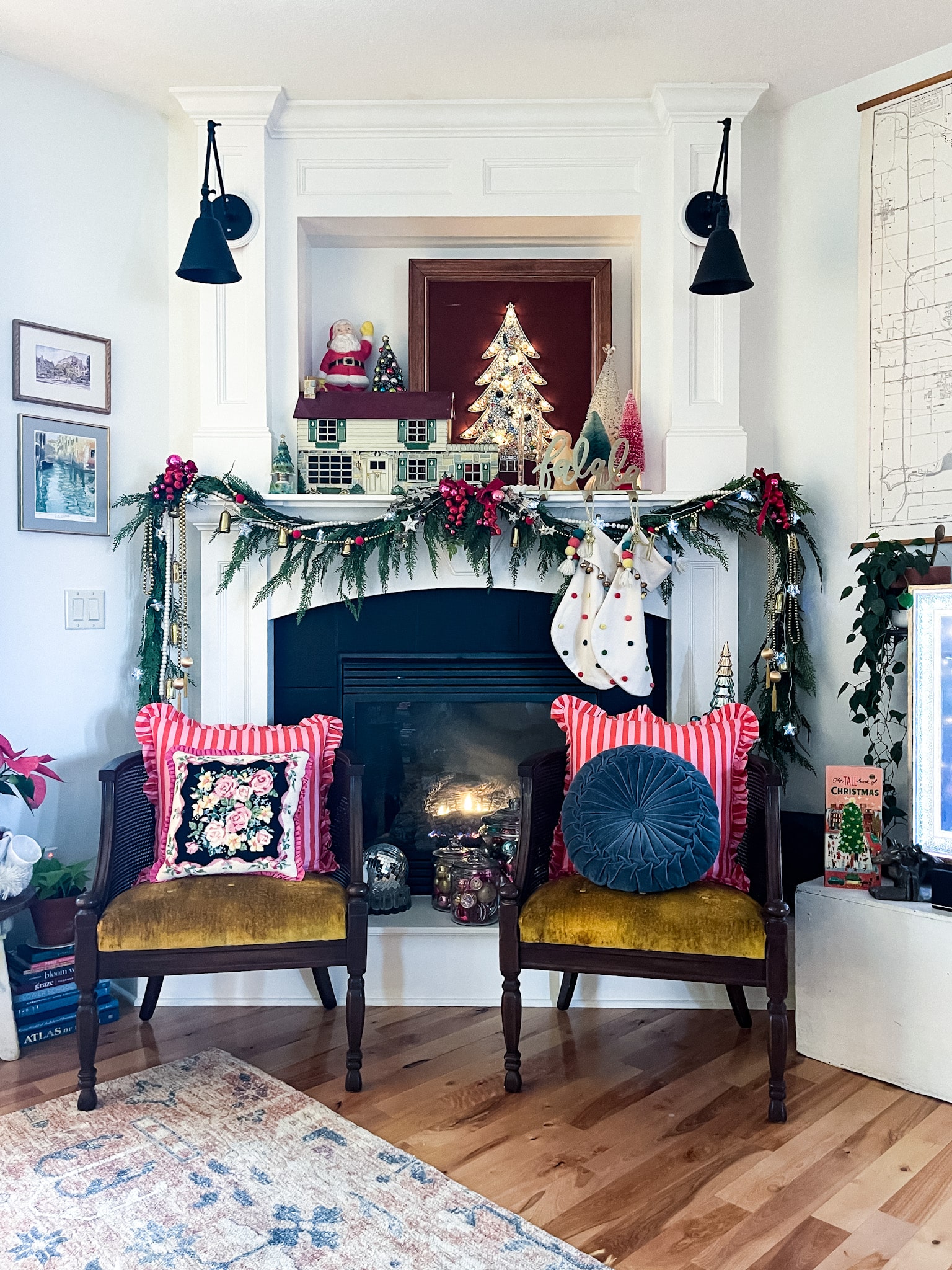fireplace and mantel decorated for christmas, two accent chairs in front with pillos, and an art tv