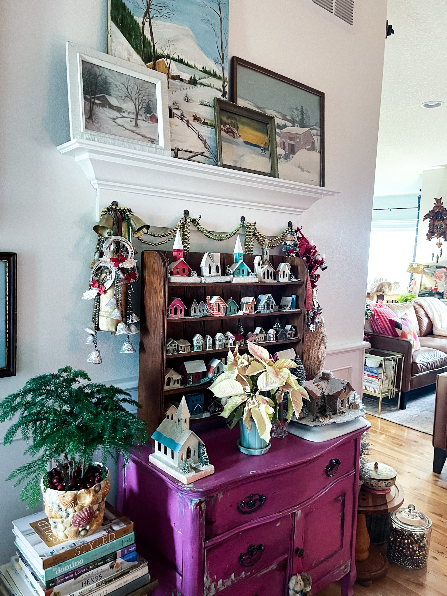 fuchsia commode decorated with vintage christmas decor, including putz houses, mercury glass garland, and plants