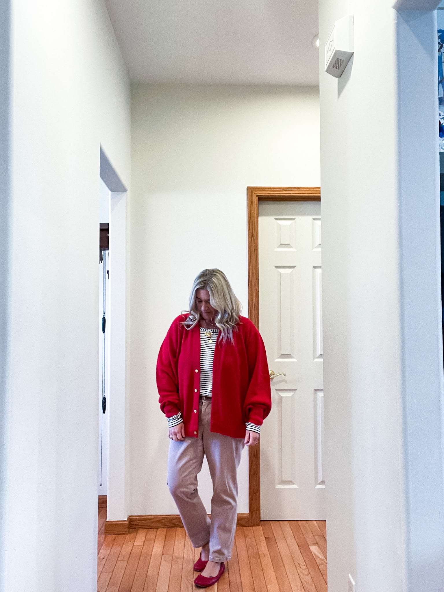 woman in a red sweater, black and white striped shirt, pink pants, and red shoes