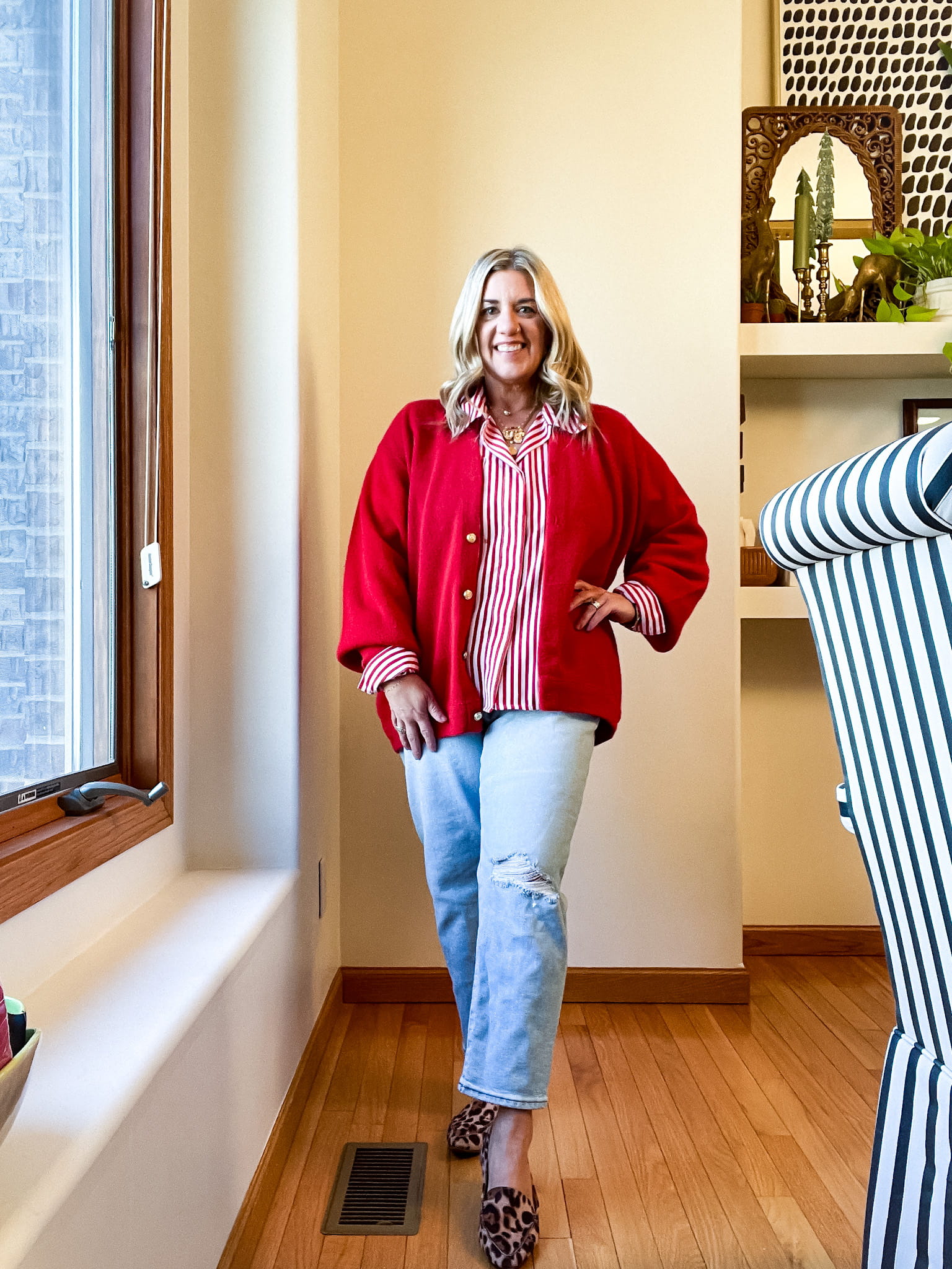 woman in a red blazer/sweater, red and white shirt, jeans, and leopard shoes