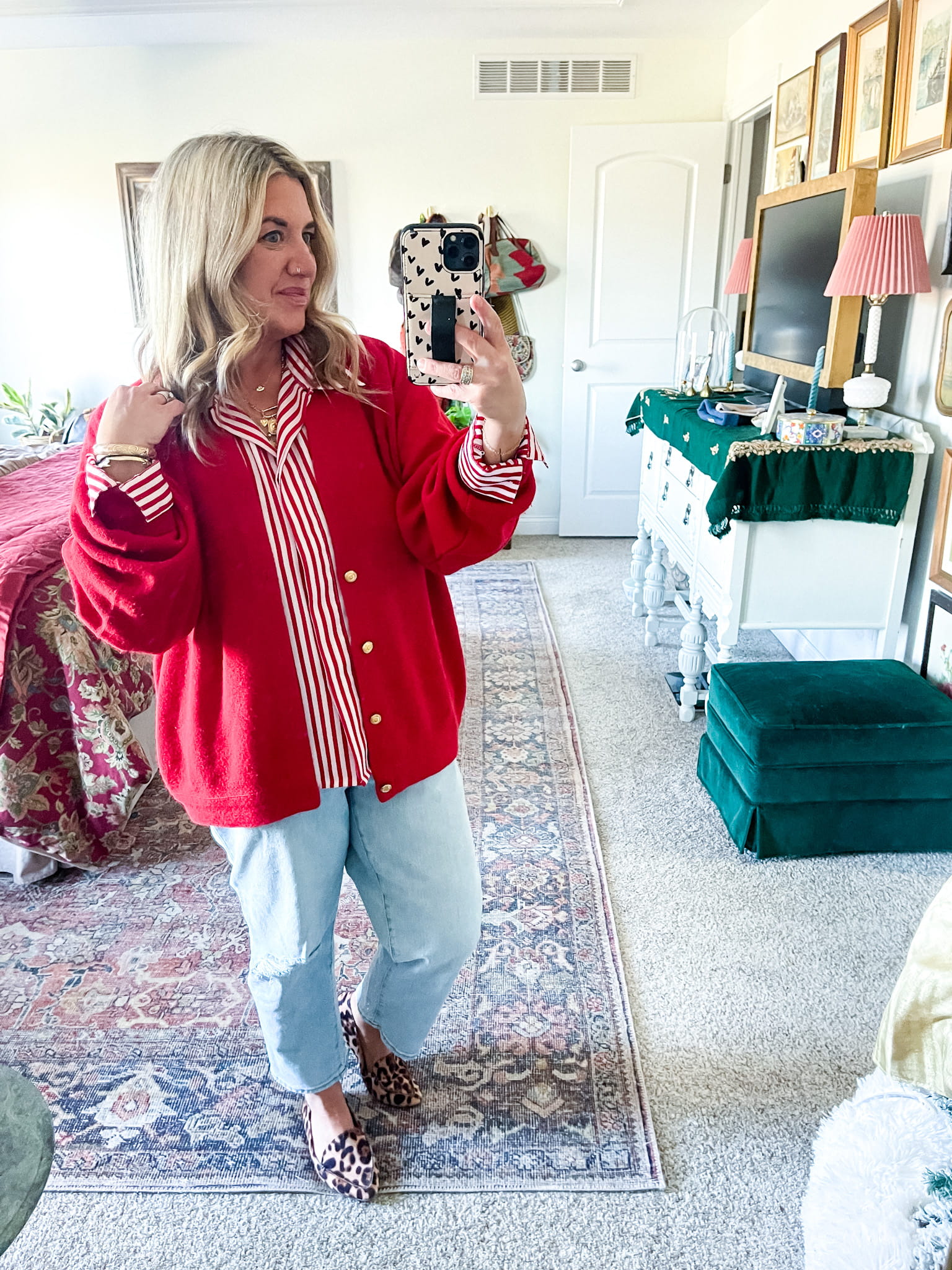 woman in a red blazer/sweater, red and white shirt, jeans, and leopard shoes