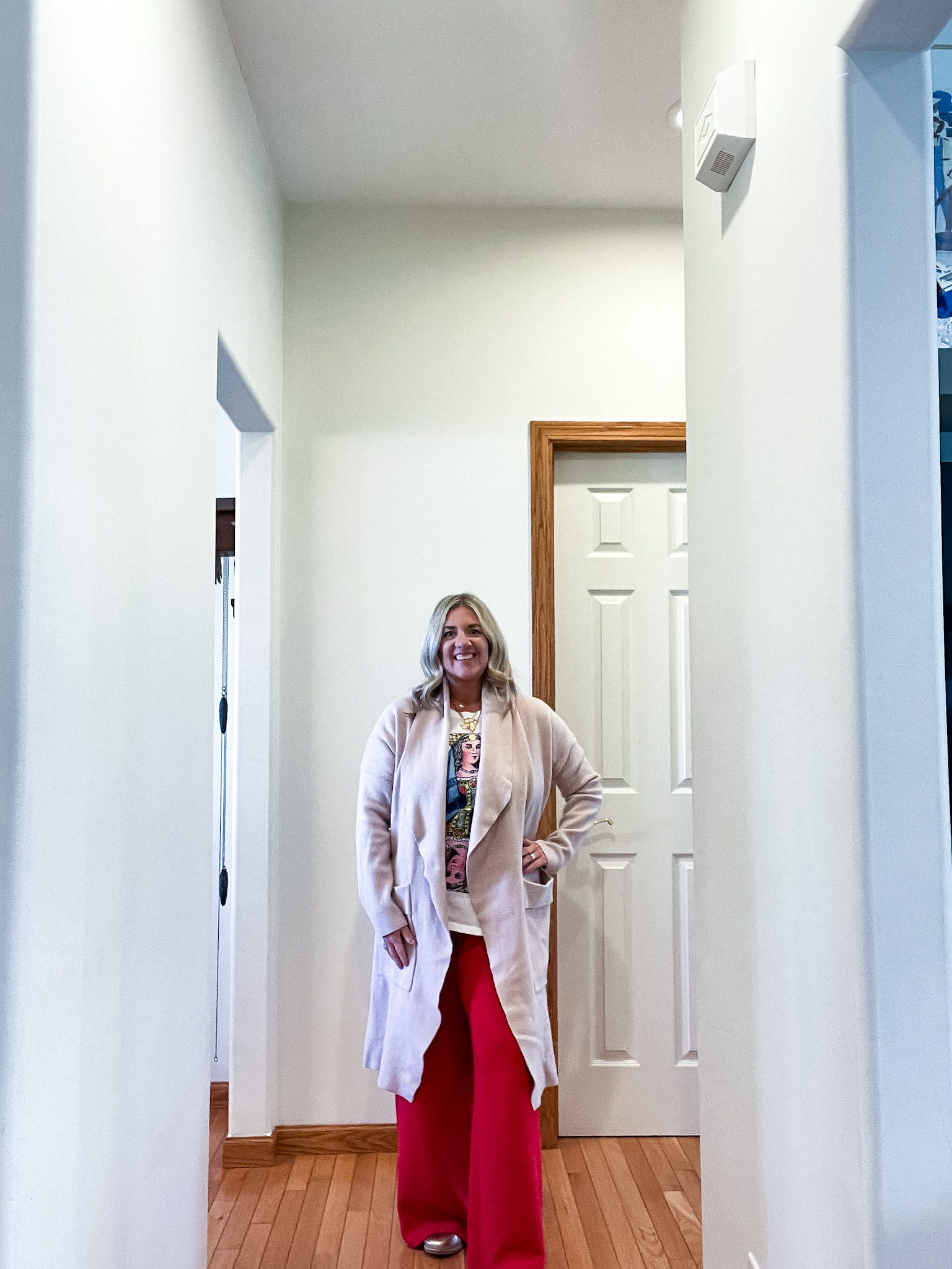 woman in a pink sweater, graphic t-shirt, red trousers, and gold shoes