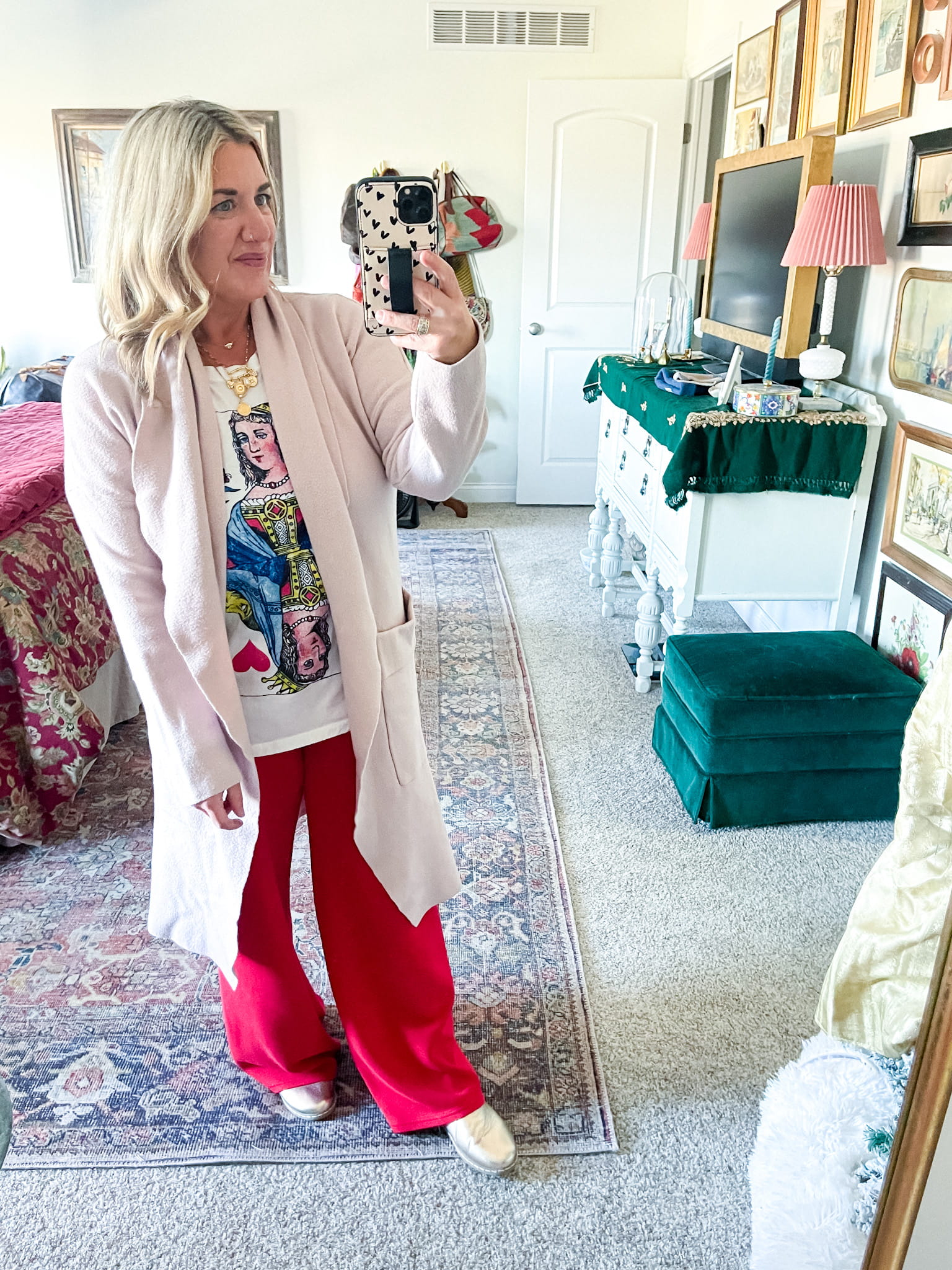 woman in a pink sweater, graphic t-shirt, red trousers, and gold shoes