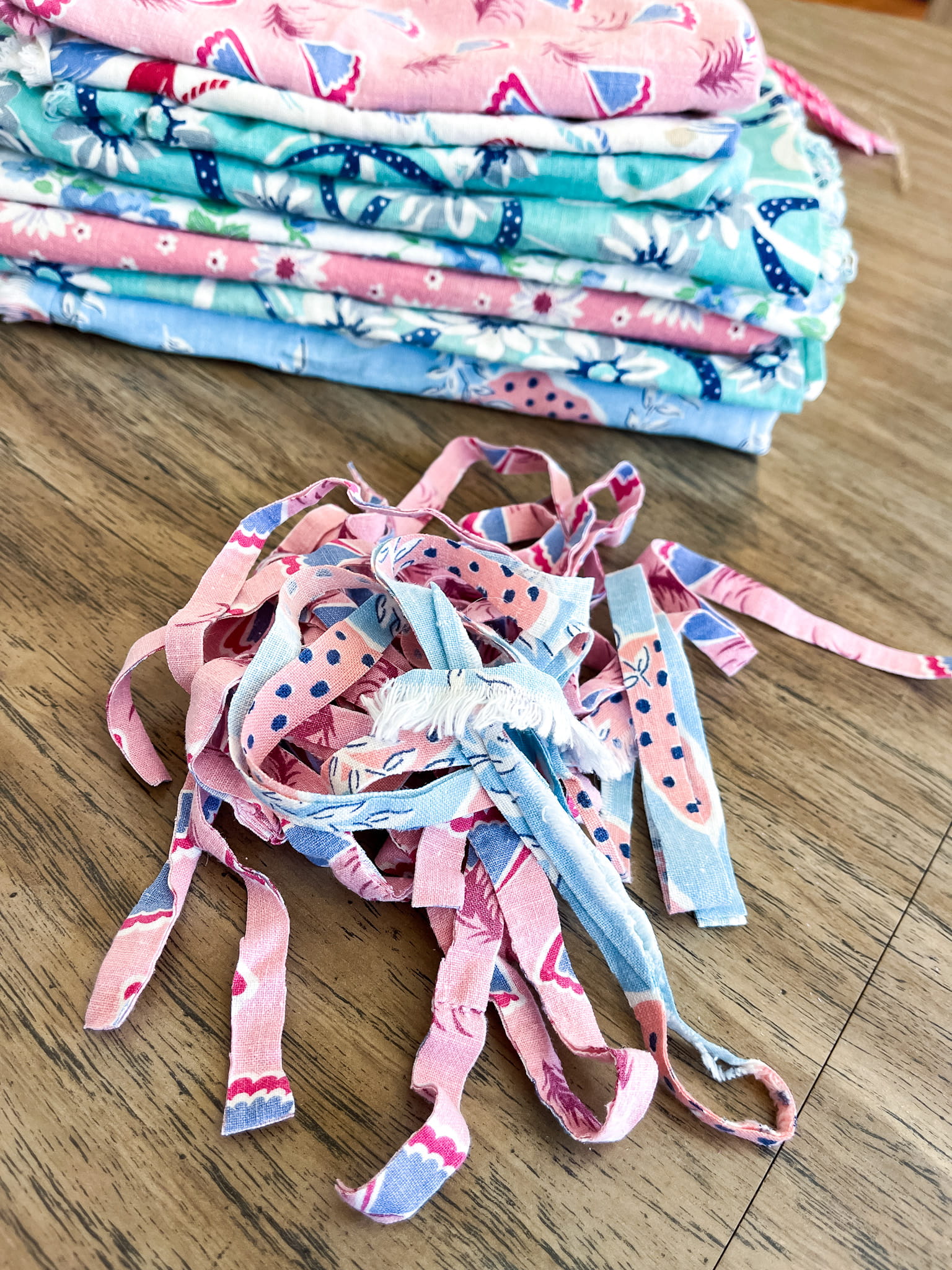 Stack of colorful vintage flour sack fabric and some cut into strips