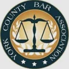 Logo for the York County Bar Association, featuring a central design of the scales of justice surrounded by a wreath and the association name.