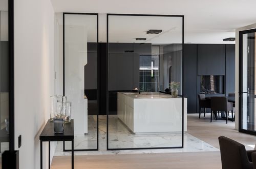 Binnenraam met zwarte omkadering die 2 ruimtes van elkaar onderscheidt, maar niet de volledige lengte van de ruimte inneemt.