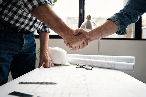 Architect and engineer construction workers shaking hands while working for teamwork and cooperation concept after finish an agreement in the office construction site, success collaboration concept