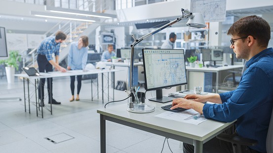 In the Busy Engineering Facility: Diverse Group of Engineers, Technicians, Working on Design for Industrial Engine Prototype. Specialists Talk During Meetings, Work with Drawings, Use Computers