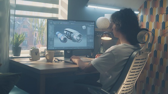 Male young engineer using pc with professional program and creating 3D prototype of airplane turbine while working remotely at home office