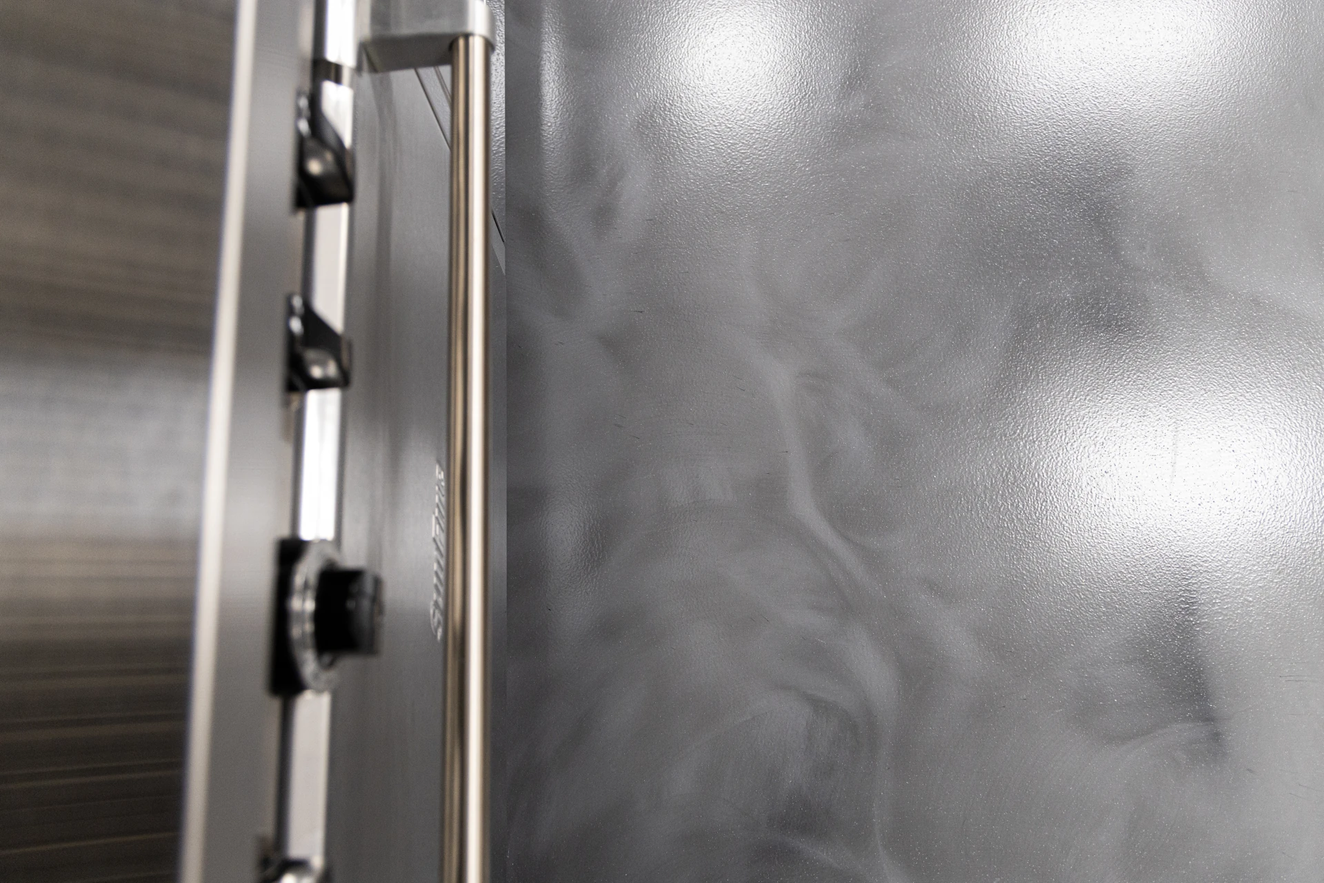 Close-up of metallic epoxy floor showing smooth, swirled silver-gray pattern beside stainless steel equipment