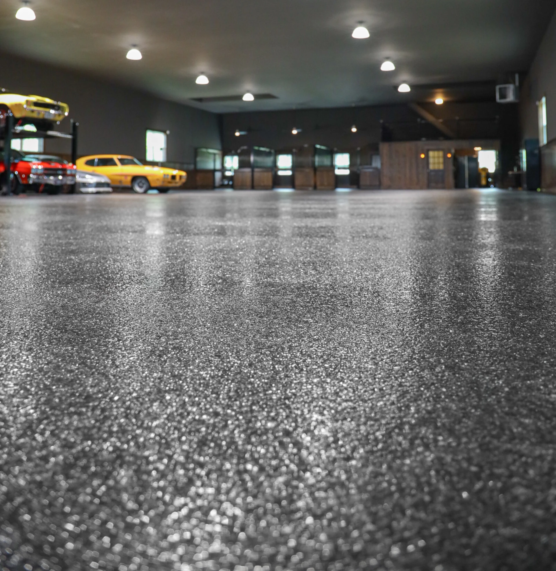 Low-angle view of a clean, reflective polyaspartic flake floor surface in a well-lit multi-car garage.