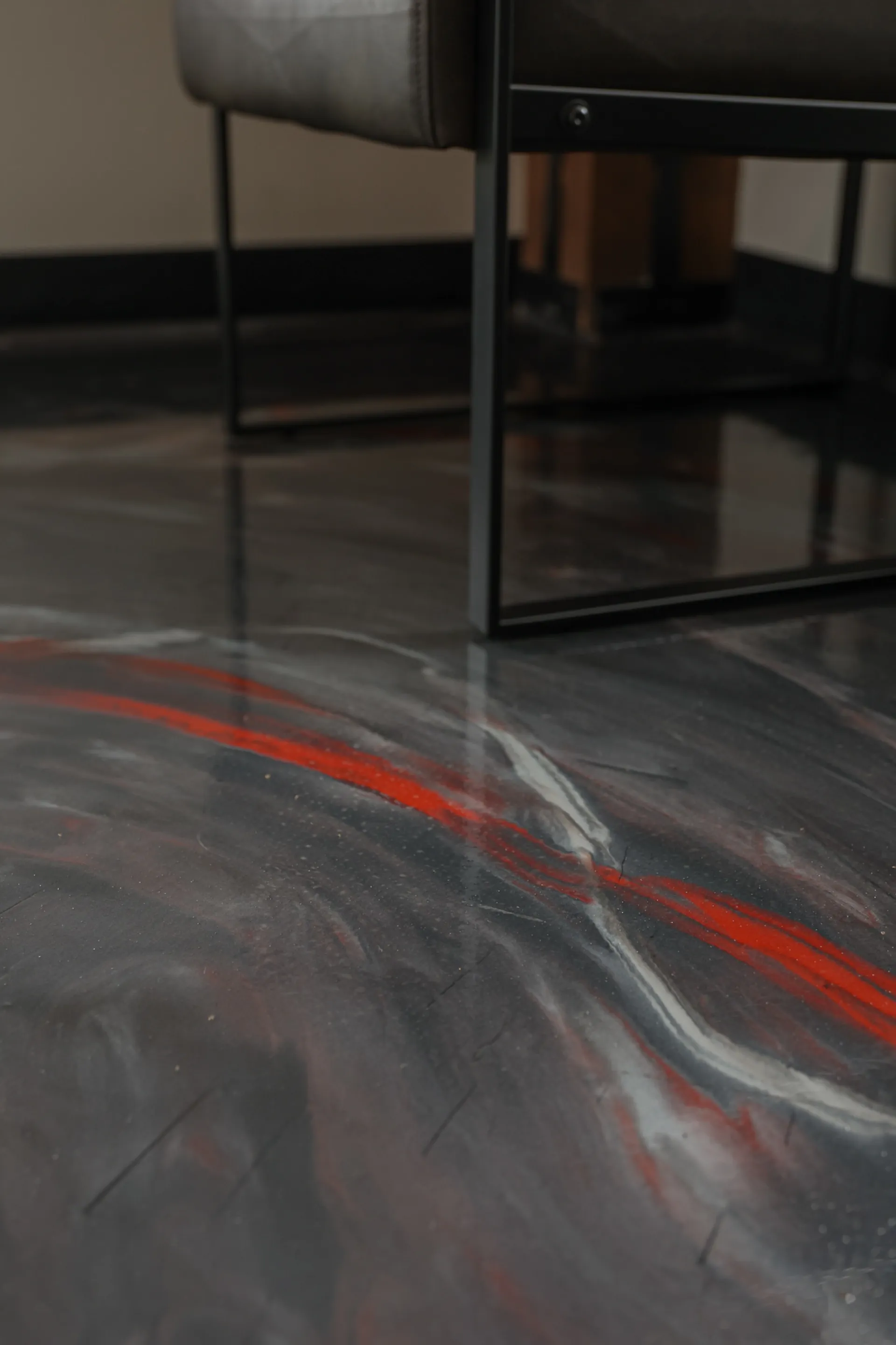 Close-up of a chair on the high-gloss metallic epoxy floor showing custom color blend of red, charcoal, and pearl at Holmes Manufacturing.