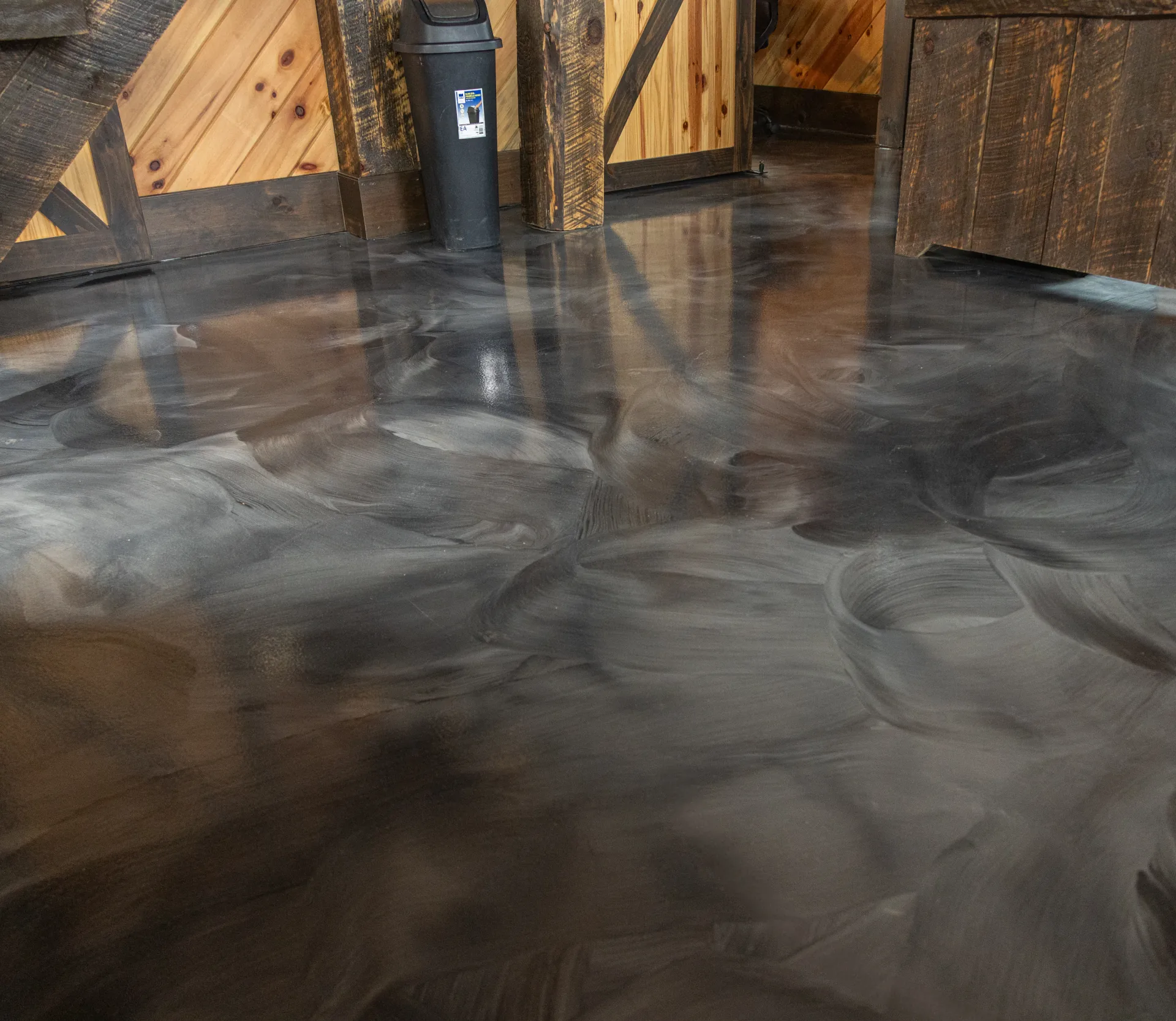 Corner view showing flowing swirl and reflection on silver and charcoal metallic epoxy floor in Miller Brothers Hardwood showroom, Salesville Ohio.