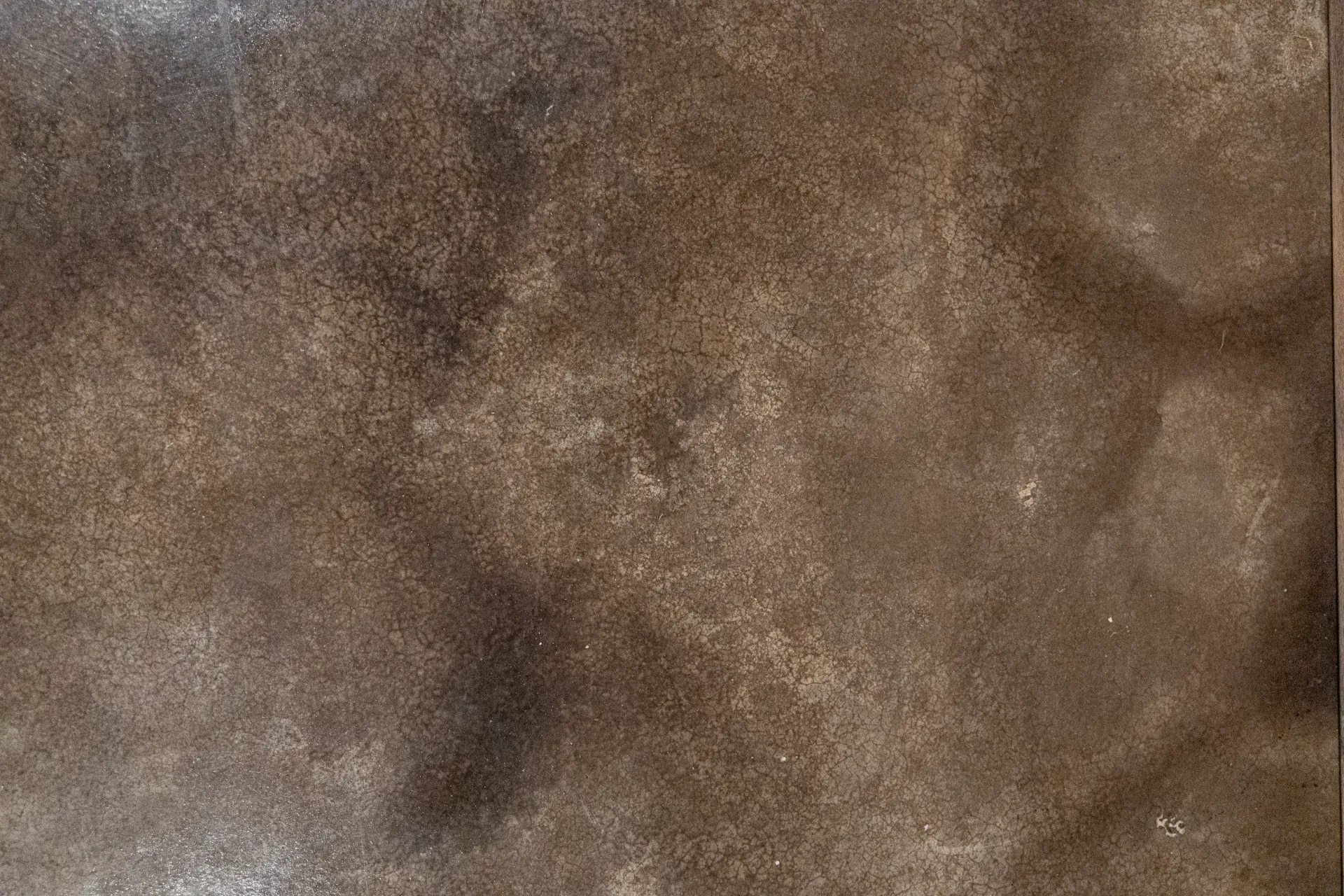 Detailed texture of custom acid stained concrete floor with dark earth-tone finish in residential basement.