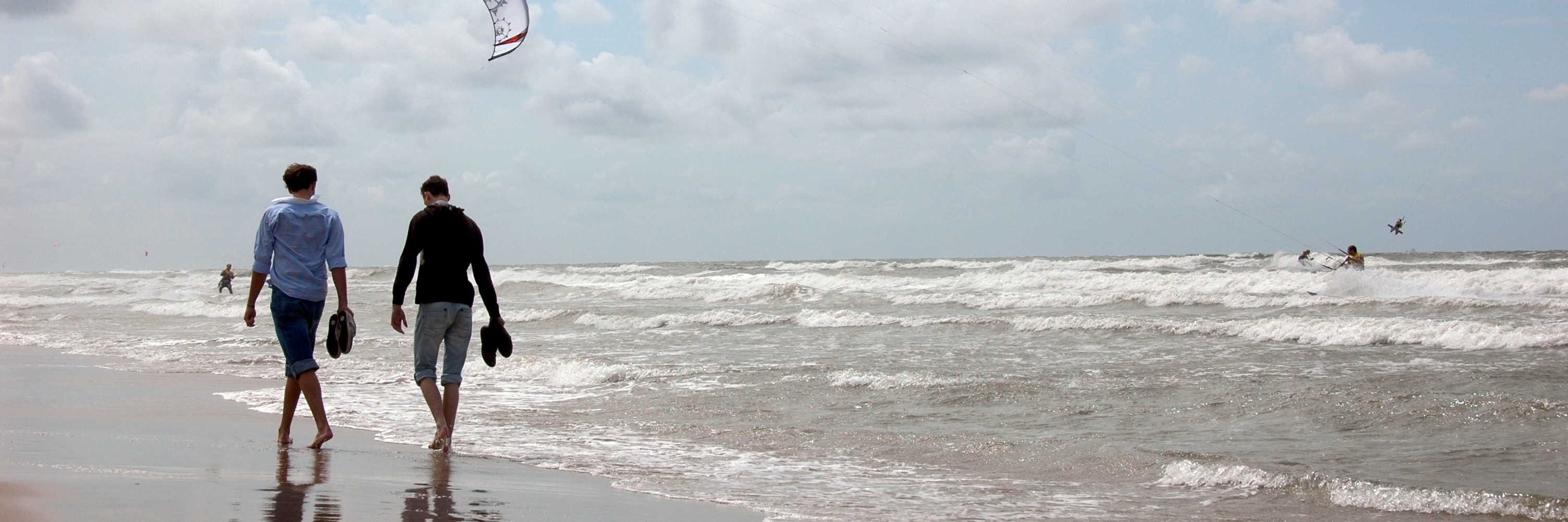 Twee wandelaars langs de vloedlijn op het strand van Noordwijk