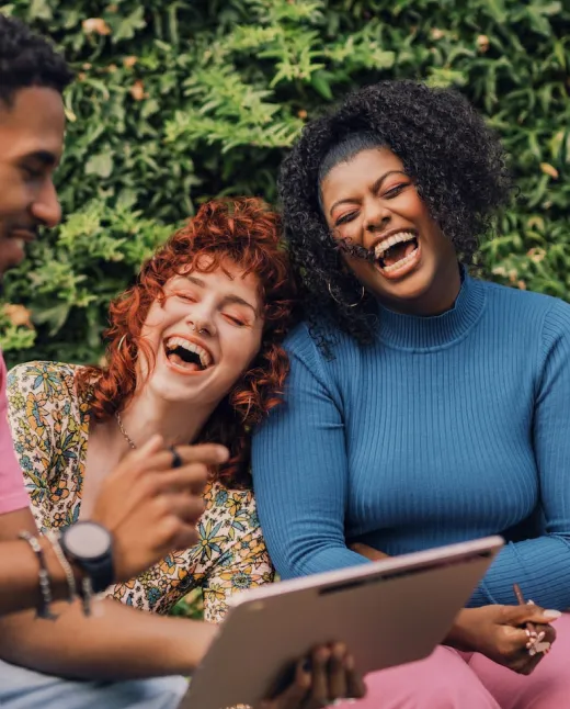 A black woman and white red head laughing, enjoying their time spent in leadership coaching for women