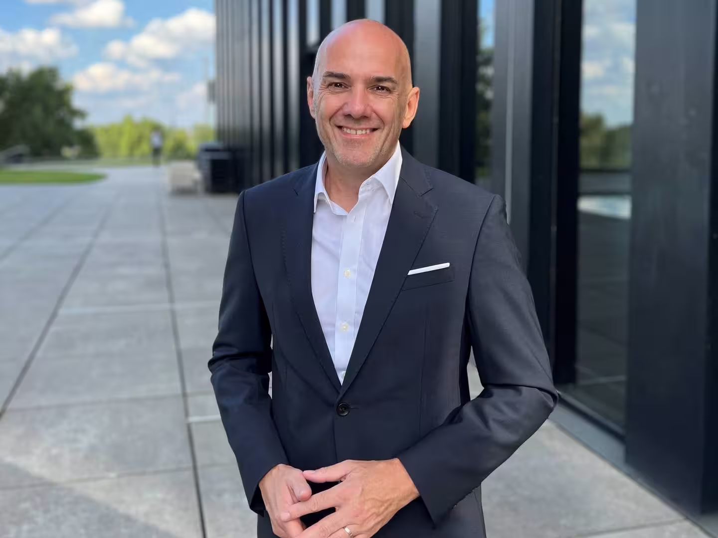 Experian CEO Jochen Werne standing outdoors in a business suit, sharing insights on post-acquisition culture and leadership.