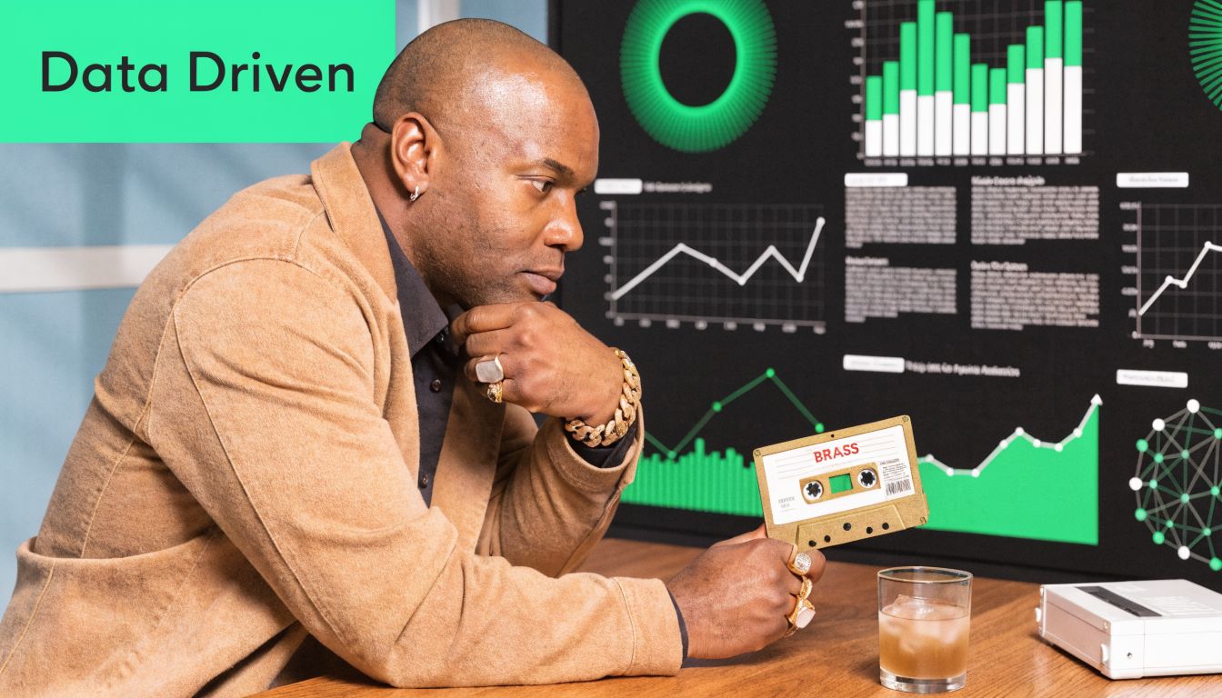 A stylish businessman in a blazer examines a vintage cassette tape labeled BRASS in front of data charts.