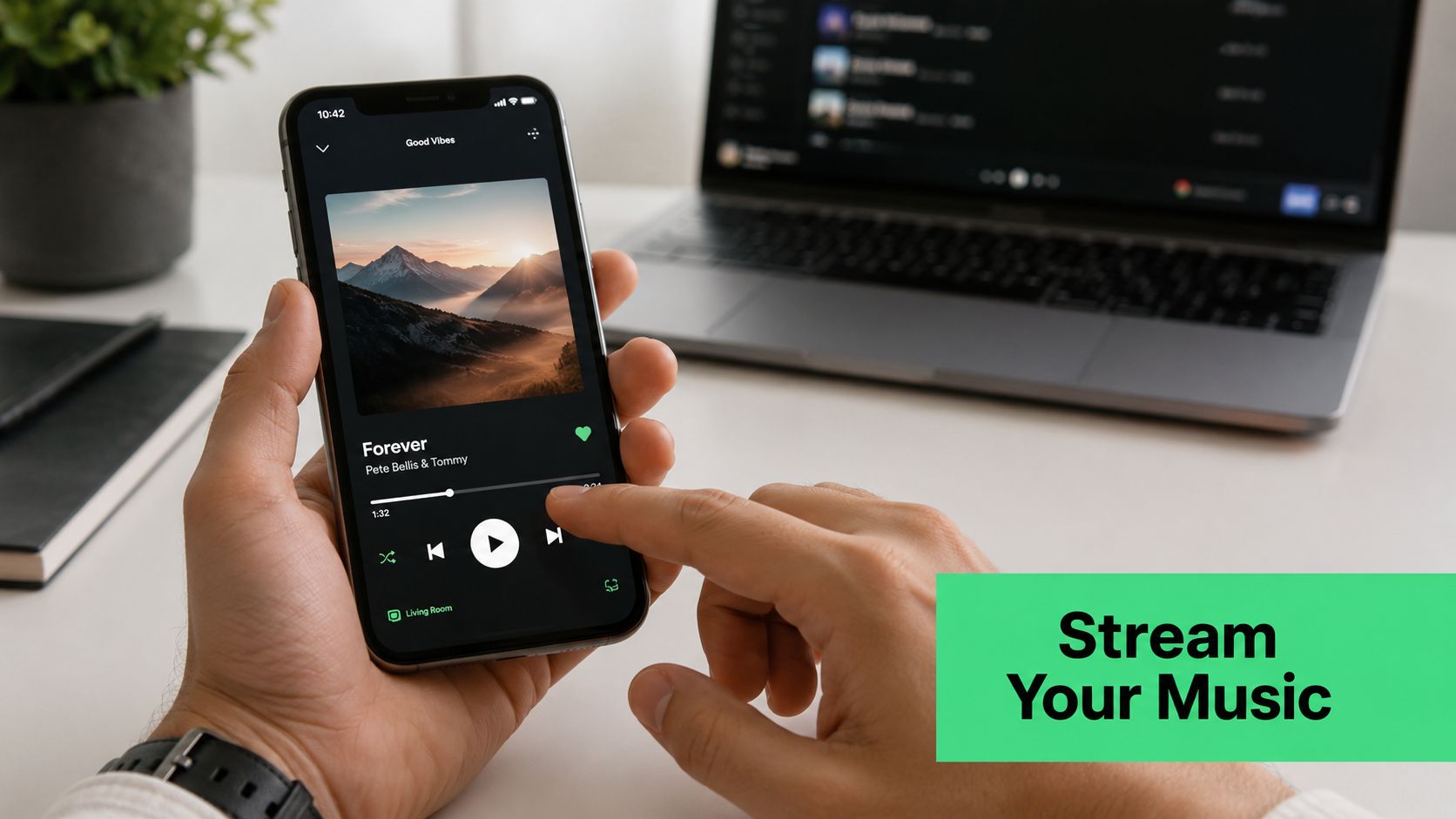 A person holding a smartphone playing music on a streaming app while working at a desk.