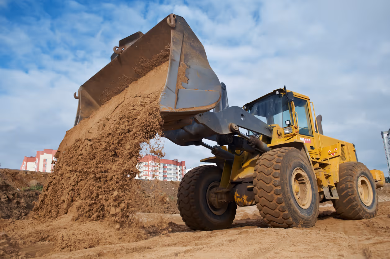 Construction loader moving soil at job site powered by off road diesel fuel.