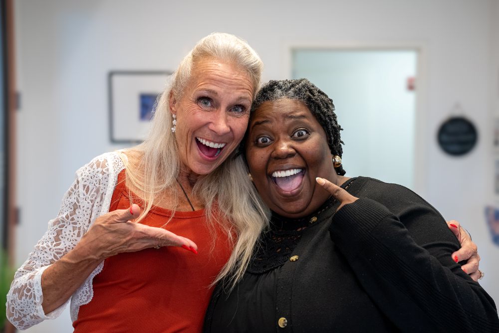 Sharala and Leslie smiling and pointing at Sharala's new teeth