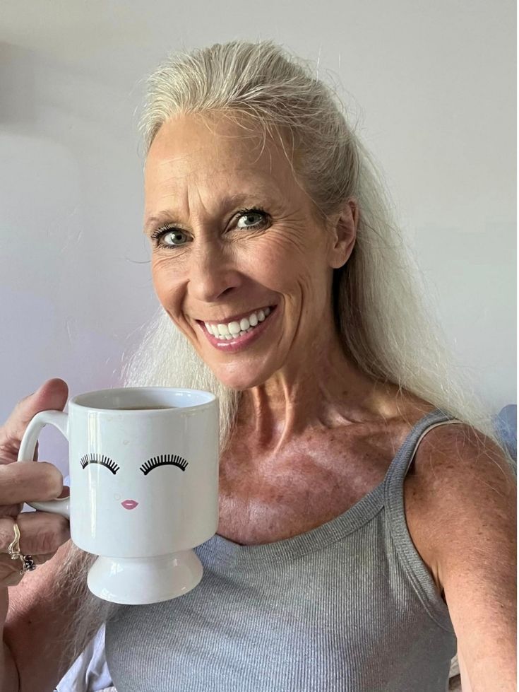 Leslie smiling with her zirconia teeth and holding a cup of coffee