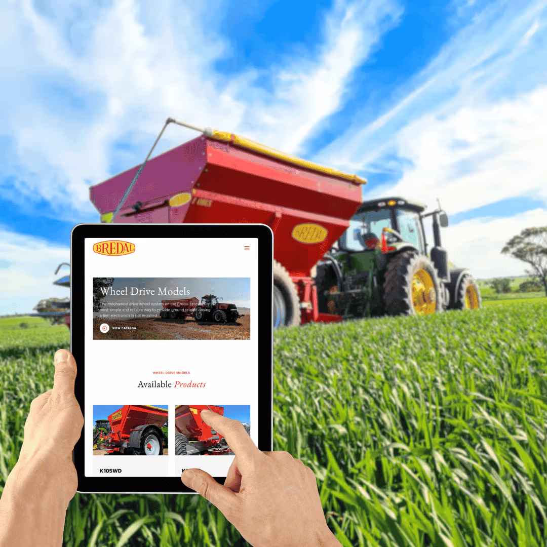Person using tablet in field with red farm machinery